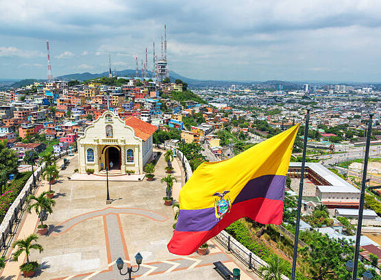 Ecuadorian flag on top of Santa Ana hill with a church and the city of Guayaquil visible in the background in Ecuador
